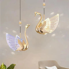 Gold swan-shaped pendant lights on a neutral background