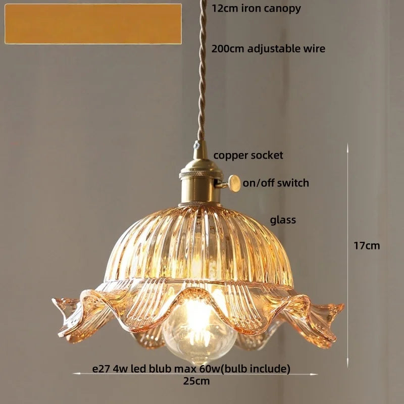 Decorative pendant light with clear glass shade and gold metal fixture on a neutral background.