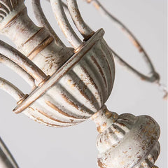 Detailed close-up of the central body of a distressed white iron chandelier, highlighting its ornate texture and finish.