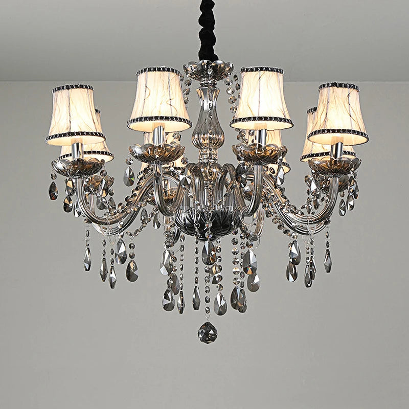 A close-up view of a smoke gray crystal chandelier with fabric shades and cascading crystal droplets against a white ceiling.