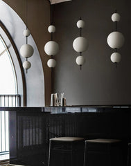 Modern interior with black bar, white spherical pendant lights, and dark walls.