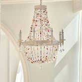 White multi-arm chandelier with cascading colorful beads and clear crystals, hanging from a white ceiling.