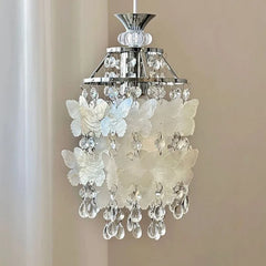 Side view of a chrome pendant light adorned with white butterfly shell decorations and crystal droplets.