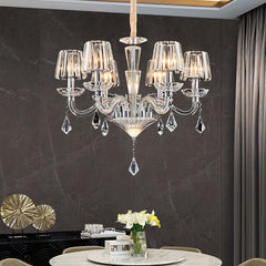 A crystal chandelier with candle-style arms, illuminated and installed in a dining room setting.