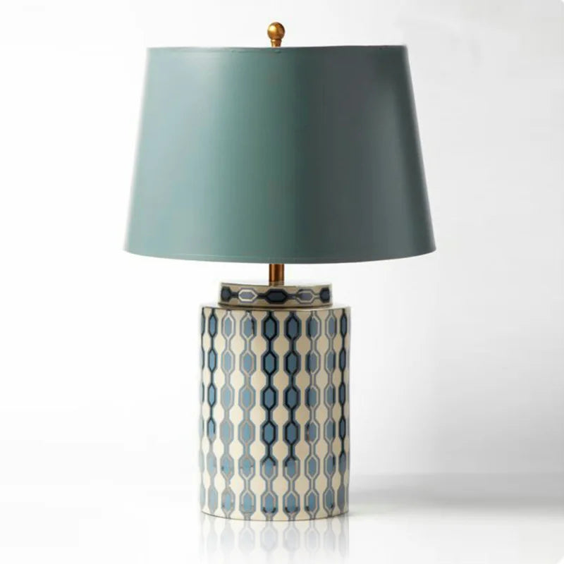 Close-up of a blue and white geometric patterned ceramic table lamp base with a light blue fabric shade against a white background.