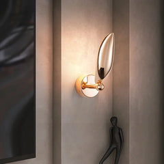 Modern wall sconce with leaf design on a textured wall.