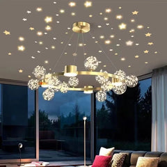 View of a gold starburst chandelier in a living room at night, with stars visible on the ceiling and the chandelier's lights reflecting.