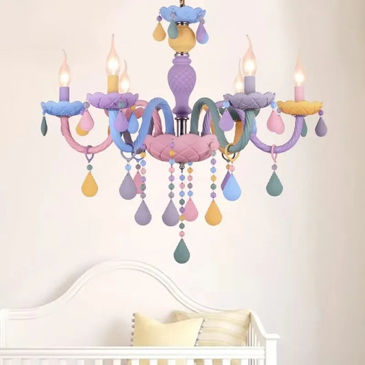 Close-up of a pastel-colored crystal chandelier with floral accents and candle-style lights, mounted in a nursery setting.