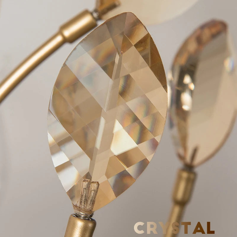 Close-up of a faceted amber crystal detail on a brushed gold chandelier arm.