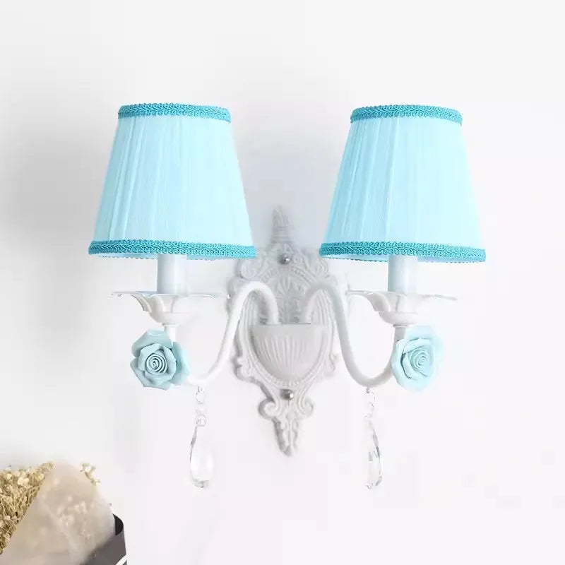 White double wall sconce with blue pleated fabric shades, adorned with blue roses and crystal droplets.