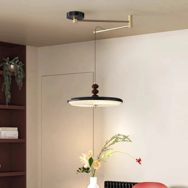 Modern pendant light fixture hanging in a room with a vase of flowers on a table.
