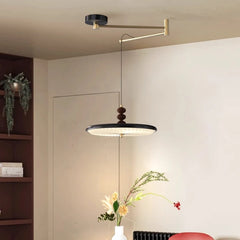 Modern pendant light fixture hanging in a room with a vase of flowers on a table.