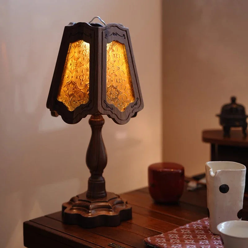 A table lamp with a textured glass shade and a dark wooden stand is displayed on a wooden surface.