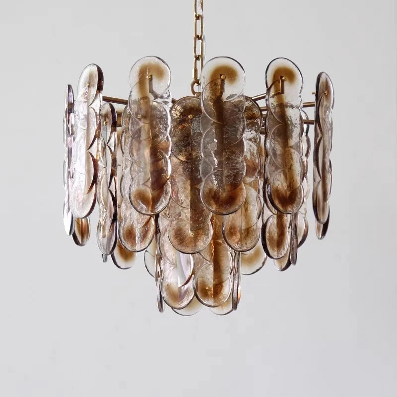 Detailed view of the amber glass discs and gold metal structure of a cascading pendant light.