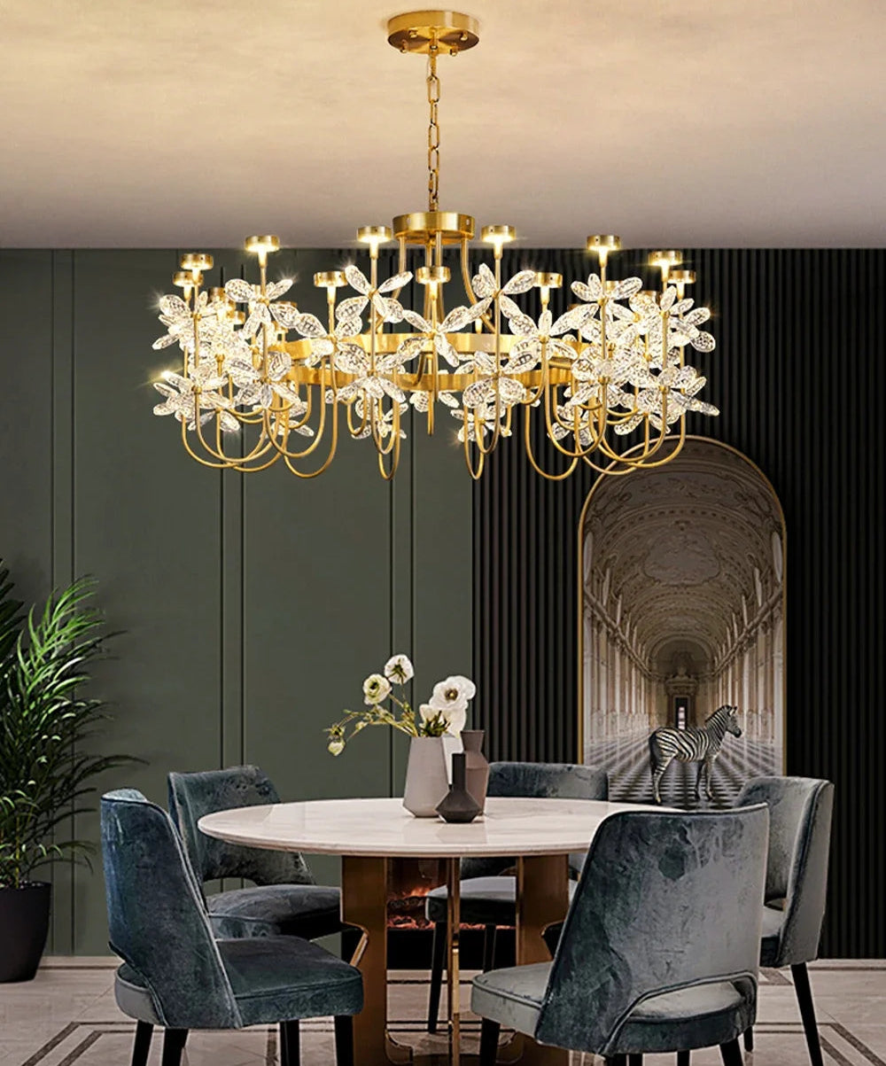 Luxurious dining room with a gold chandelier, marble table, and gray chairs.