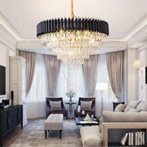 A large, tiered crystal chandelier with a gold frame hangs from a ceiling in a modern living room.