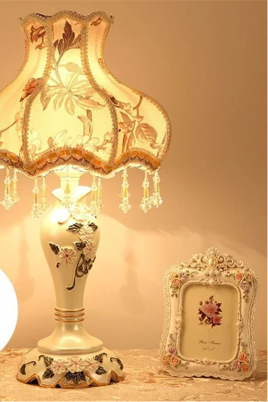 Decorative table lamp with floral design on a wooden surface, featuring a light bulb and remote control.