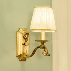 A single gold wall sconce with a pleated white fabric shade, mounted on a pale green wall.