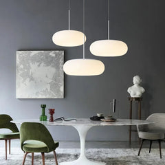 Three white oval pendant lights hanging over a dining table