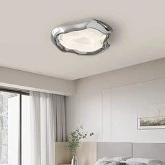 A modern chrome wave ceiling light fixture installed in a bedroom setting.