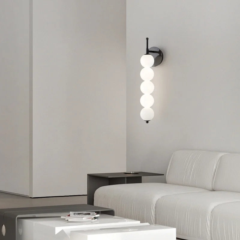 Modern wall sconce with three spherical lights in a minimalistic living room.