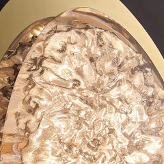 Close-up view of the textured resin insert within the gold frame of the egg-shaped wall sconce.