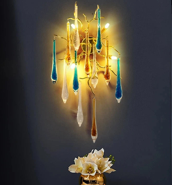 Decorative wall light fixture with colorful glass elements on a dark wall.
