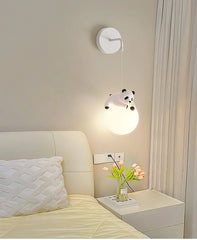 Panda-shaped pendant light above a bed in a bedroom setting