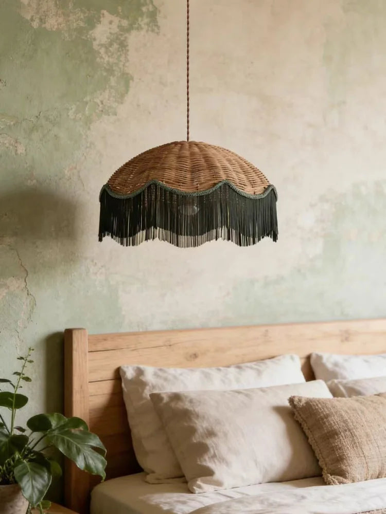 Woven rattan dome pendant light with a dark fringe hanging above a bed in a bedroom with textured walls
