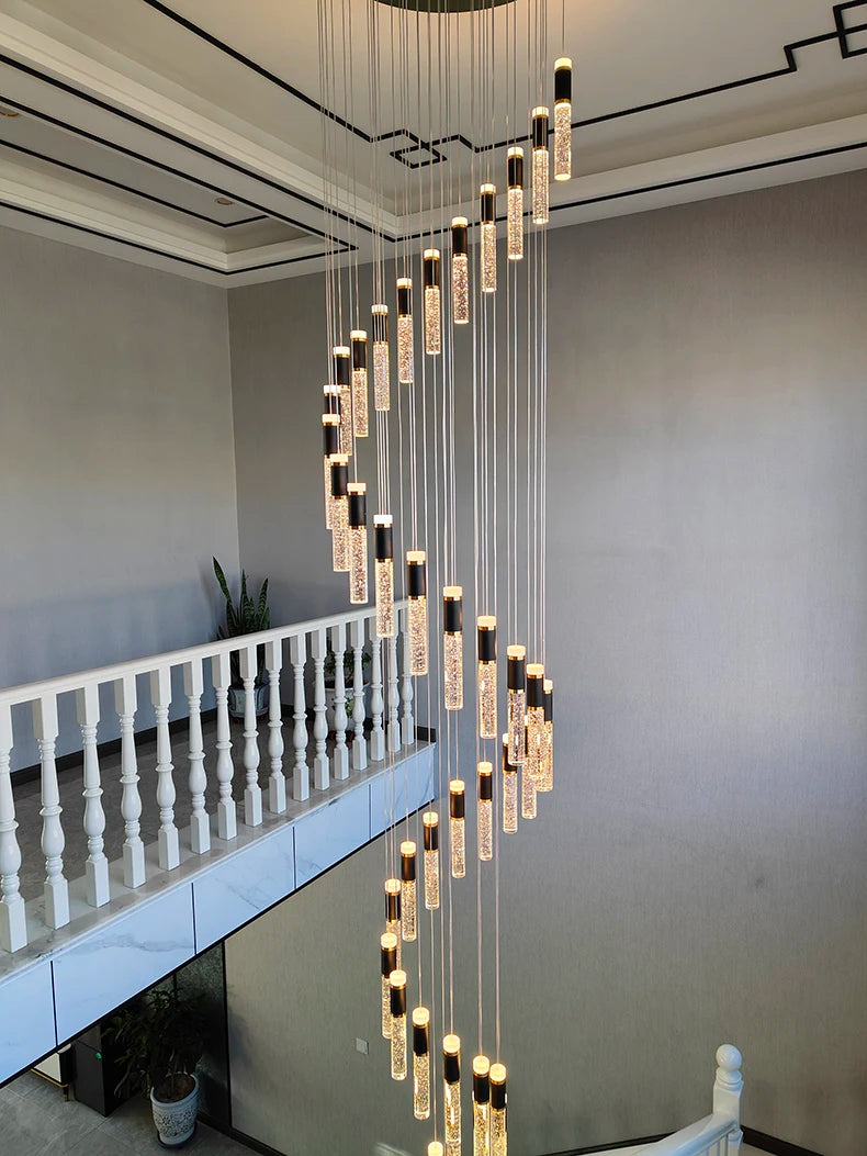 Modern chandelier hanging in a room with a staircase and white railing.