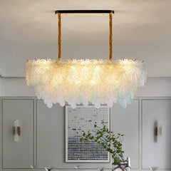A long, oval-shaped chandelier with clear crystal leaf elements and subtle blue tips, hanging from gold cords.