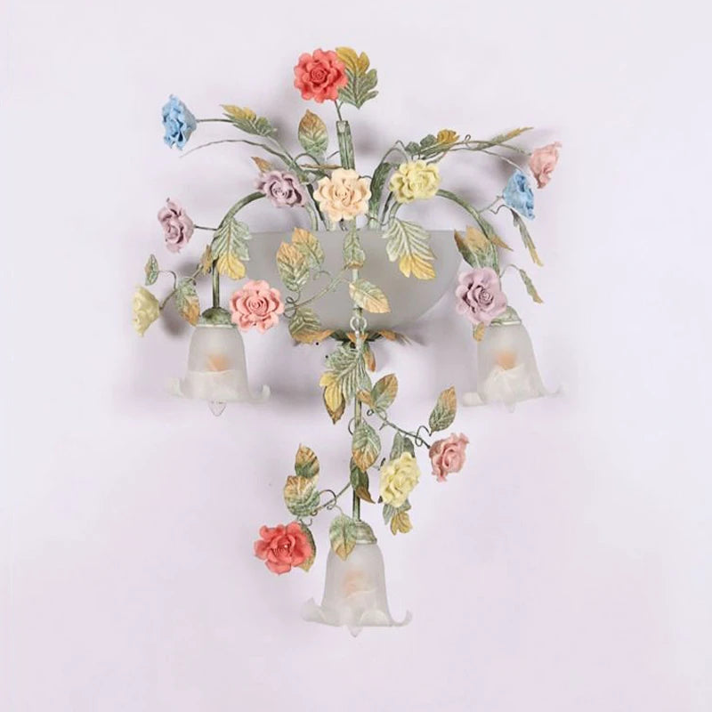 The gold floral wall sconce installed on a white wall, with soft light illuminating the surrounding area.