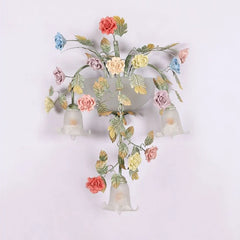 The gold floral wall sconce installed on a white wall, with soft light illuminating the surrounding area.