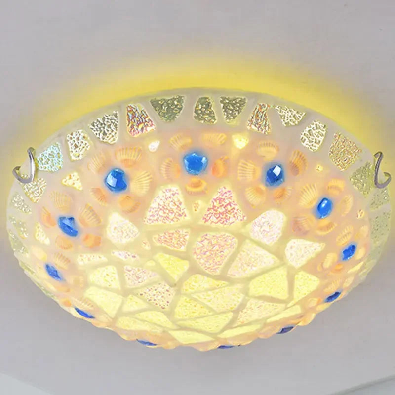 Side view of a mosaic glass seashell flush mount ceiling light emitting a warm yellow glow