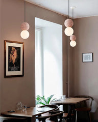 Modern interior with pendant lights, tables, chairs, and framed artwork on a wall.