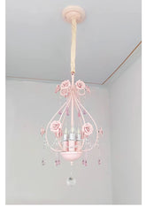 A pink crystal chandelier with rose accents hanging from a ceiling.