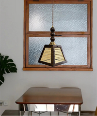 Wooden pendant light hanging in front of a glass-paneled wooden window.