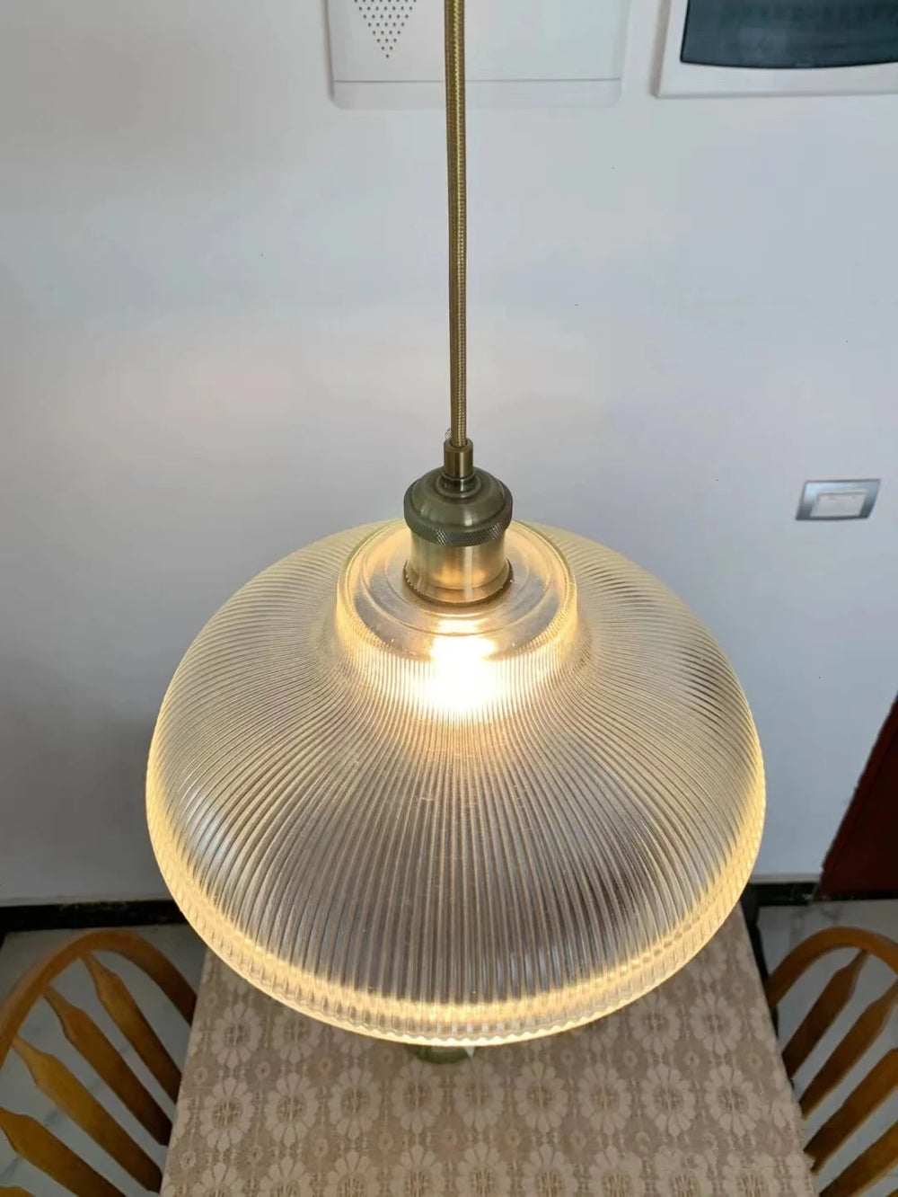Pendant light with ribbed glass shade and brass fixture on a neutral background