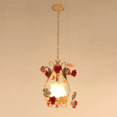 A single gold floral pendant light with red rose accents and a frosted glass shade, hanging from a chain against a plain background.