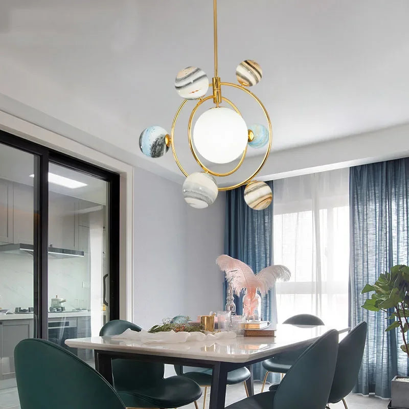 Modern chandelier hanging above a dining table in a stylish room with kitchen and window view.