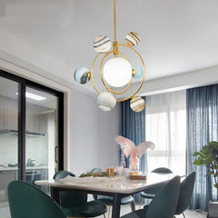 Modern chandelier hanging above a dining table in a stylish room with kitchen and window view.