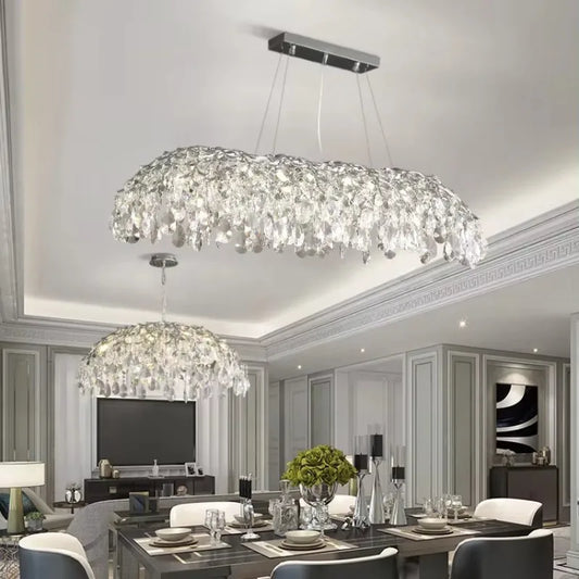 A large, multi-tiered chrome chandelier with cascading crystals over a dining room table.