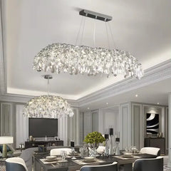 A large, multi-tiered chrome chandelier with cascading crystals over a dining room table.