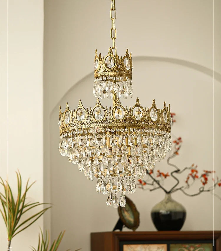 Gold and crystal chandelier hanging in a room with decor elements.