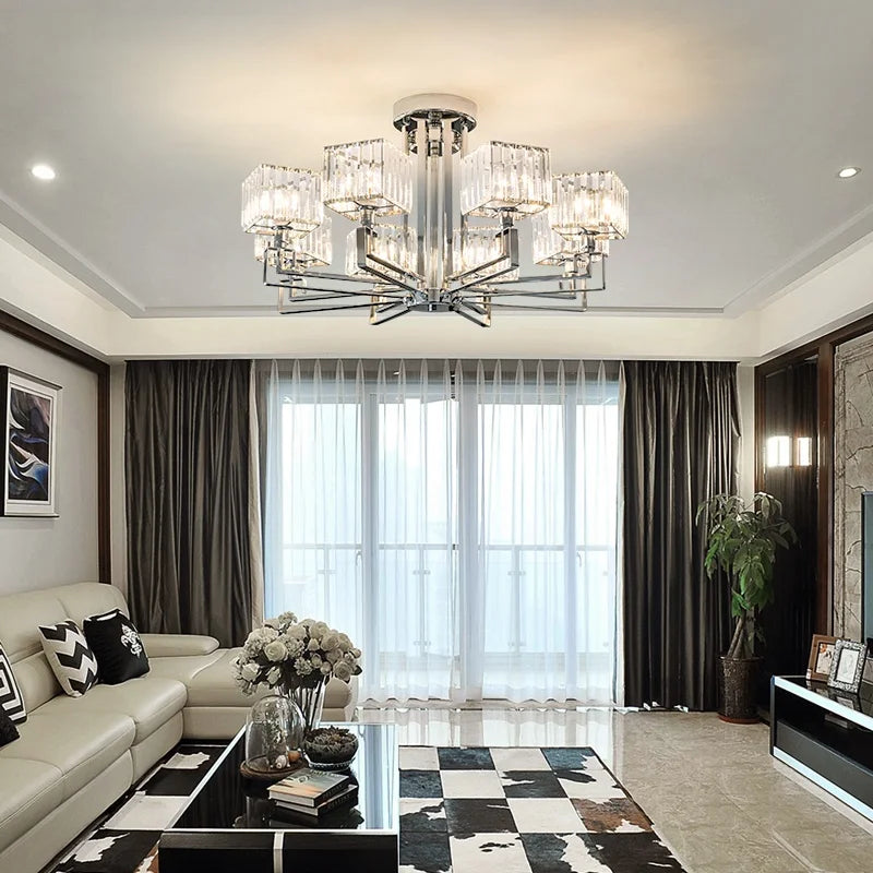 A polished chrome multi-arm crystal chandelier installed in a modern living room with large windows.