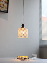 Small pendant light with a checkered glass shade hanging above a table with food.