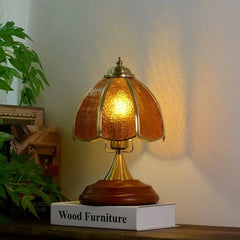 Side view of a brass table lamp with a textured amber glass shade, emitting a warm, inviting light.