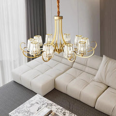 Wide shot of a polished gold chandelier with crystal accents, suspended above a sectional sofa in a contemporary living room.