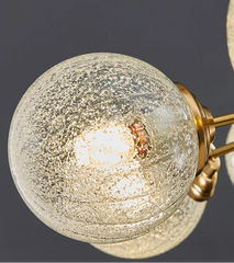 Close-up of a modern chandelier with glass globe shades and gold fixtures on a dark background.