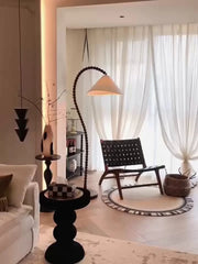 Modern living room with a black floor lamp, white sofa, and large window with white curtains.